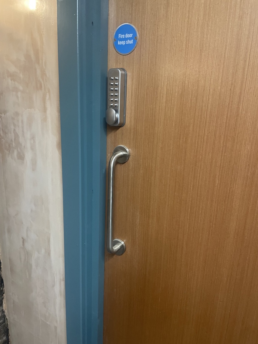 Fire doorset with access control keypad, pull handle and blue mandatory fire door sign