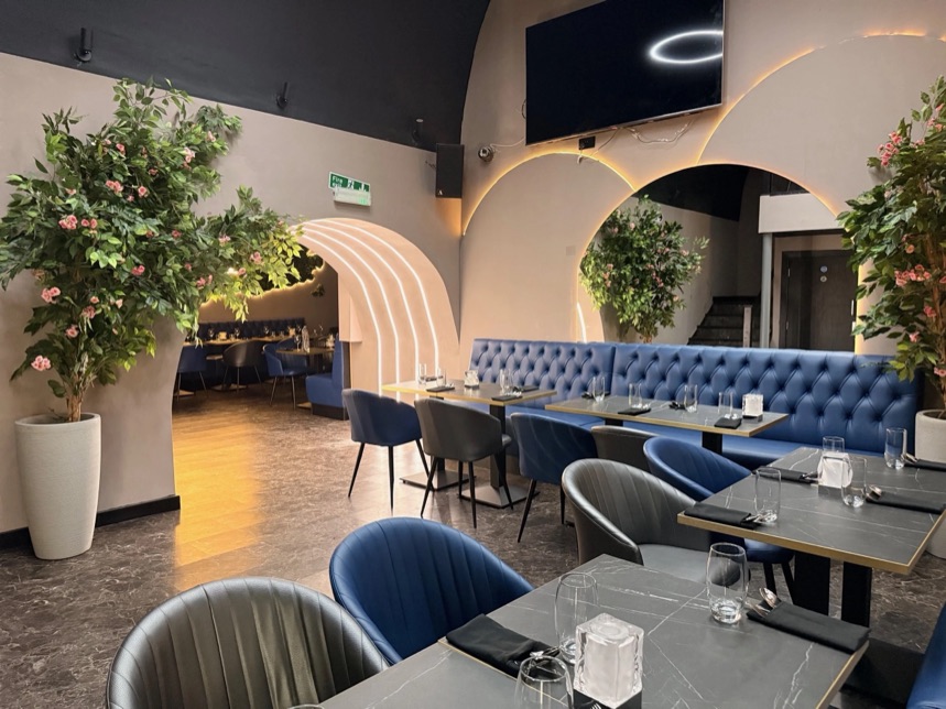 Restaurant interior with arched features, plants and blue seating