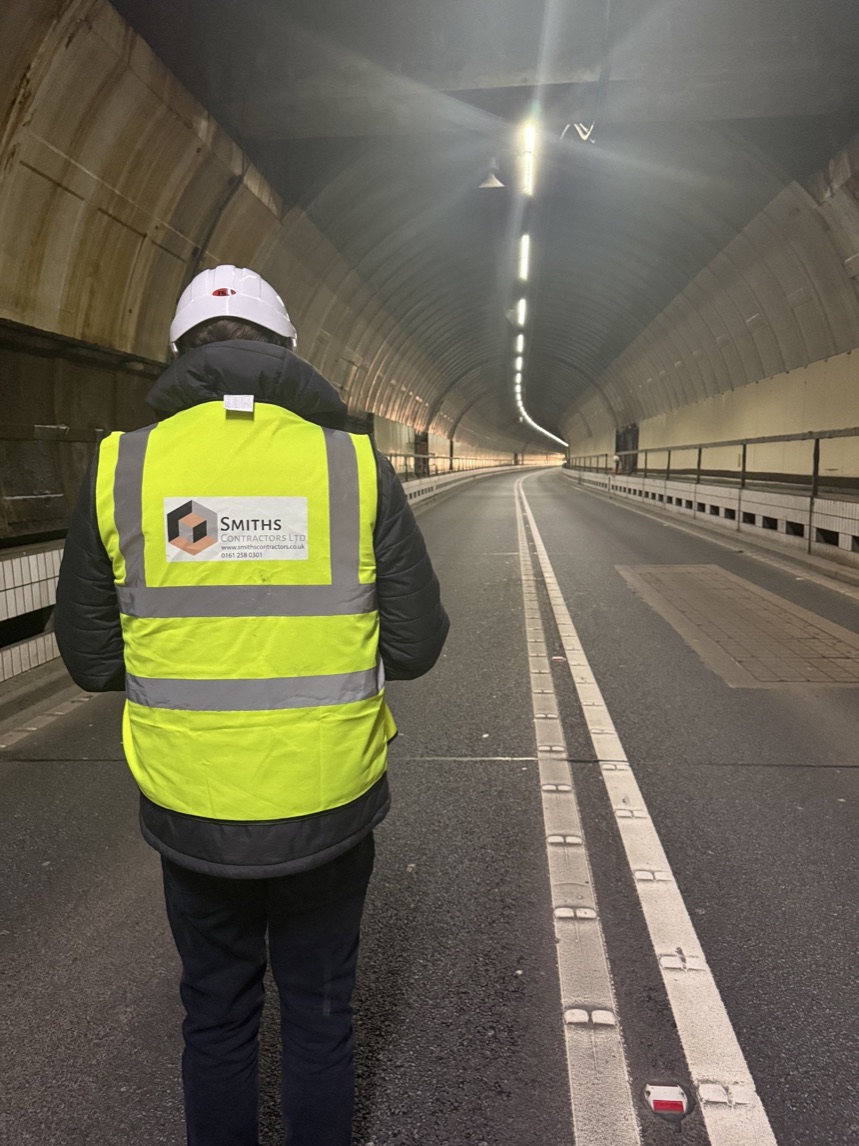 Smiths Contractors operative in hi-vis and hard hat inspecting a tunnel